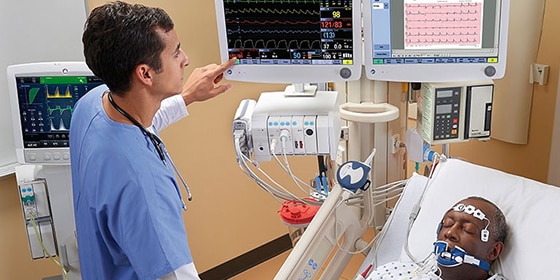 Dos cuidadores hablan cerca de una incubadora en una sala del hospital que cuenta con el monitor CARESCAPE B850 de GE Healthcare que muestra los datos del paciente en la pantalla.
